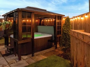 A hot tub in a wooden gazebo with string lights. - 1 bedroom accommodation in Colchester (Colchester)