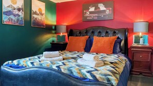 Una cama con un edredón estampado, dos almohadas y dos toallas dobladas.