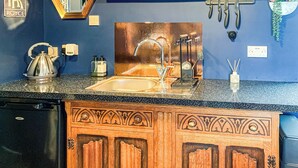 Una cocina con un lavamanos, hervidor y armarios de madera.