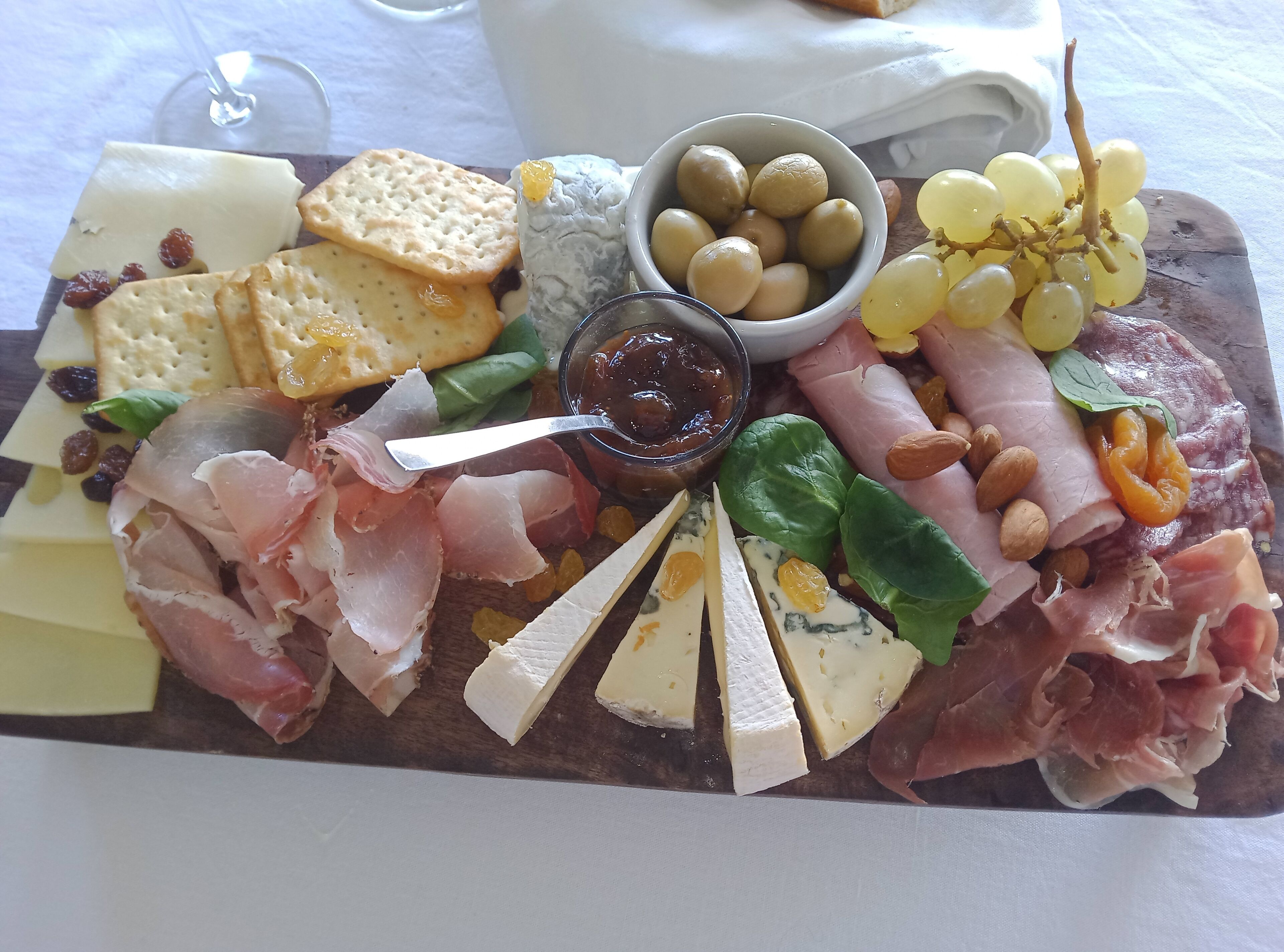 A charcuterie board with various cheeses, meats, crackers, grapes, and nuts.