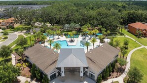 A residential area with a swimming pool, palm trees, and houses.