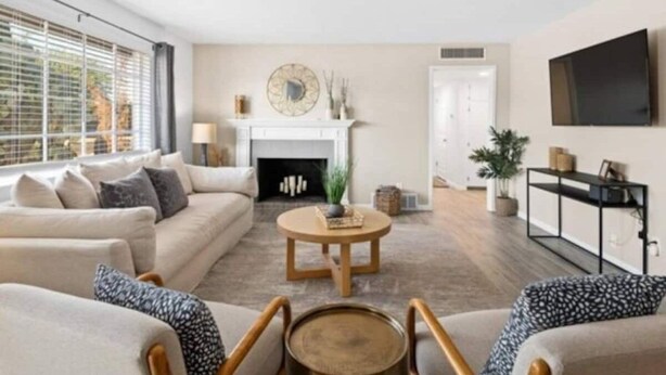 Una sala de estar con sofá, sillones, una mesa de centro, chimenea y televisor.