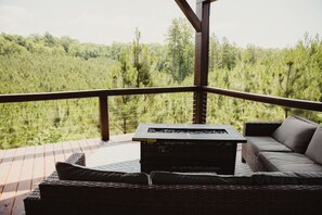 A covered outdoor seating area with a table and chairs, overlooking a forested landscape. - The Drury, Luxury Safari Tent (Cadiz)