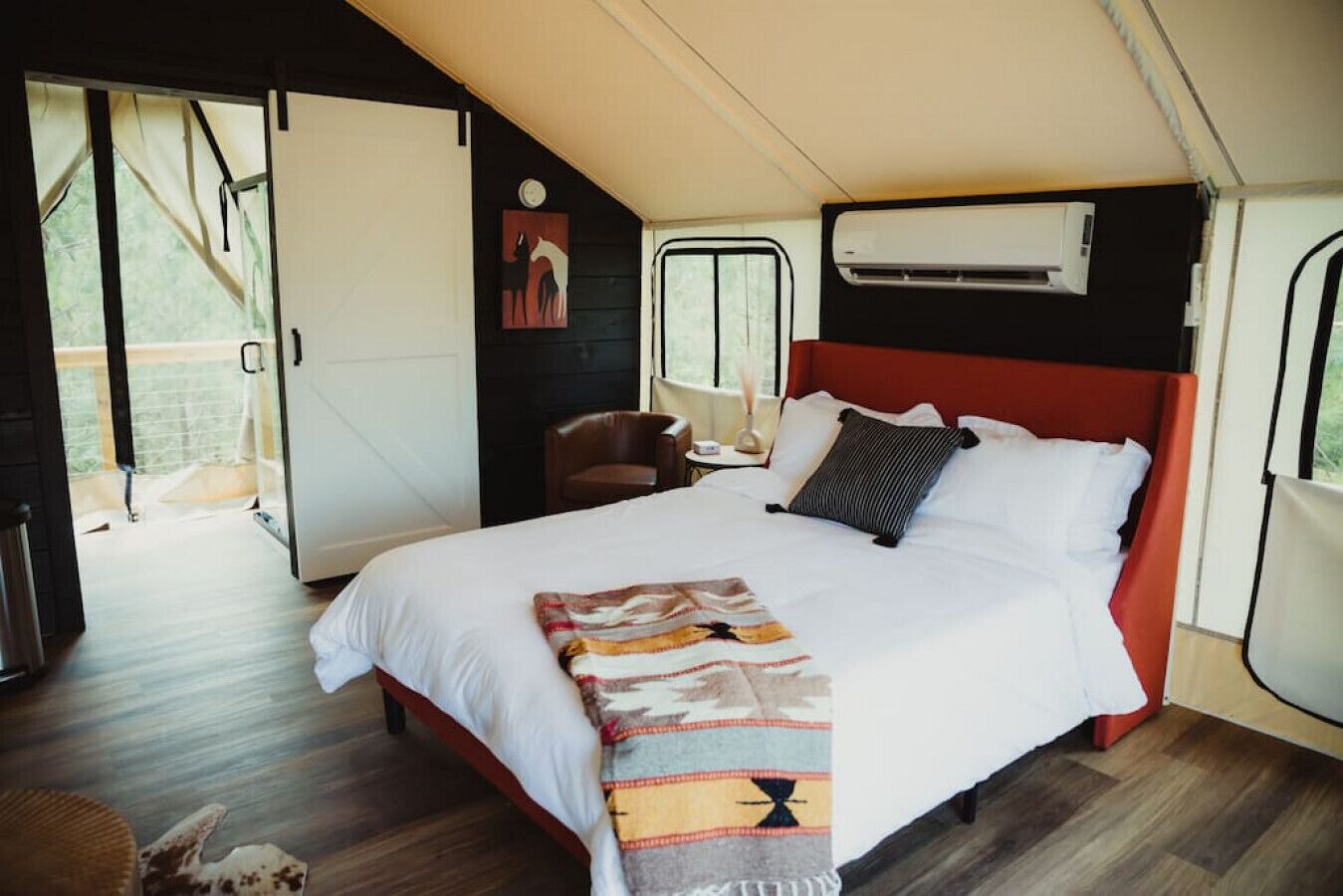 Ein geräumiges Schlafzimmer mit einem großen Bett, einem roten Kopfteil und einer Klimaanlage an der Wand.