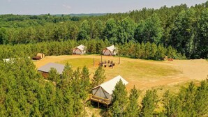 Ein Campingplatz mit mehreren Zelten und Holzhütten, umgeben von dichtem Wald.