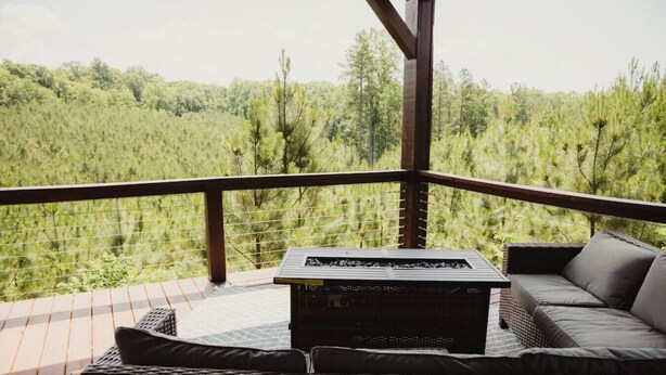 Ein überdachter Außenbereich mit Tisch und Stühlen mit Blick auf eine bewaldete Landschaft.