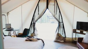 Eine Zelthütte mit Bett, Sitzecke und Fernseher.
