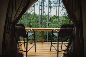 A balcony with two chairs and a wooden railing, overlooking a forested area.