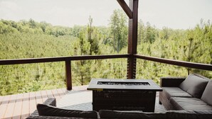 A covered outdoor seating area with a table and chairs, overlooking a forested landscape. - The Chetopa, Luxury Safari Tent (Cadiz)