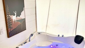 A hot tub with a digital control panel, a framed artwork above it, and a window providing natural light. - The Richbourg, Lux Safari Tent (Cadiz)