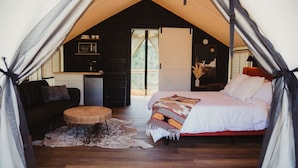 A cozy tented accommodation with a bed, a small seating area, a kitchenette, and a view of the outdoors. - The Richbourg, Lux Safari Tent (Cadiz)