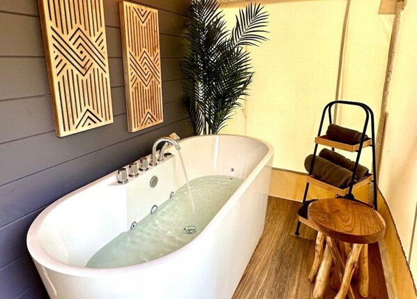 Un baño moderno con una bañera independiente, decoración de pared de madera y un taburete de madera.