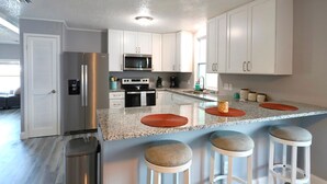 A modern kitchen with white cabinets, stainless steel appliances, and a granite countertop. - Golden Tee in North Fort Myers (North Fort Myers)