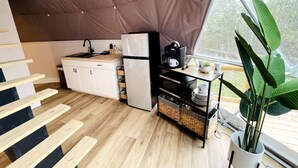 Une cuisine compacte équipée d’un réfrigérateur, d’un évier et d’un petit coin repas avec une table et des chaises.