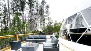 Une terrasse dotée de mobilier d’extérieur, d’un foyer et d’une structure en verre.
