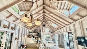 Un interior espacioso con techos altos, vigas de madera a la vista y grandes ventanales que dejan entrar luz natural.