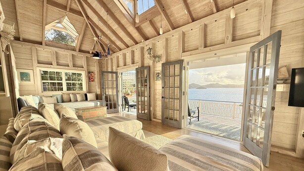 Un dormitorio amplio con una cama grande, una zona de estar con sofá y sillones, y un balcón con vistas al mar.