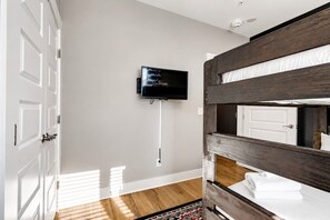 Ein Zimmer mit einem Etagenbett, einem an der Wand befestigten Fernseher und einer Tür mit Griff.
