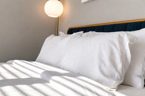 A neatly made bed with white linens and a blue headboard. - 2br home near The Nations with rooftop and views (Nashville)