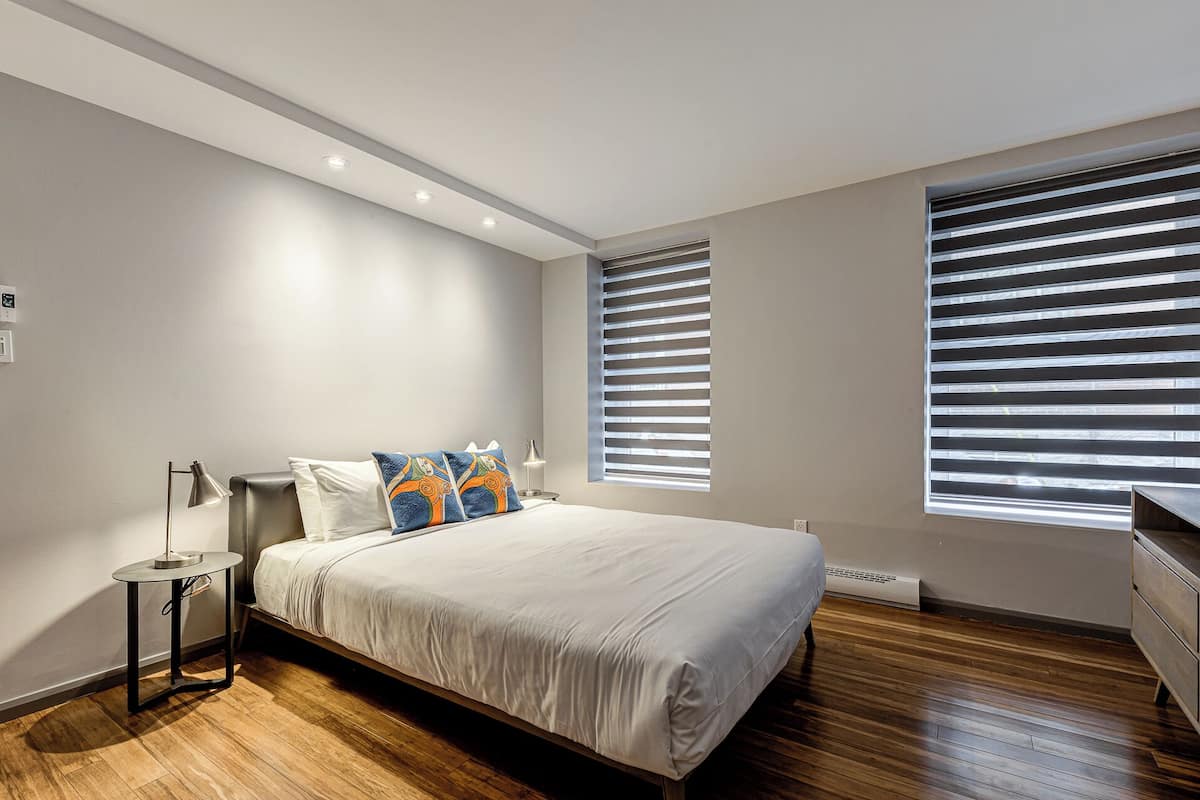 A modern bedroom with a large bed, two bedside tables, and a nightstand.