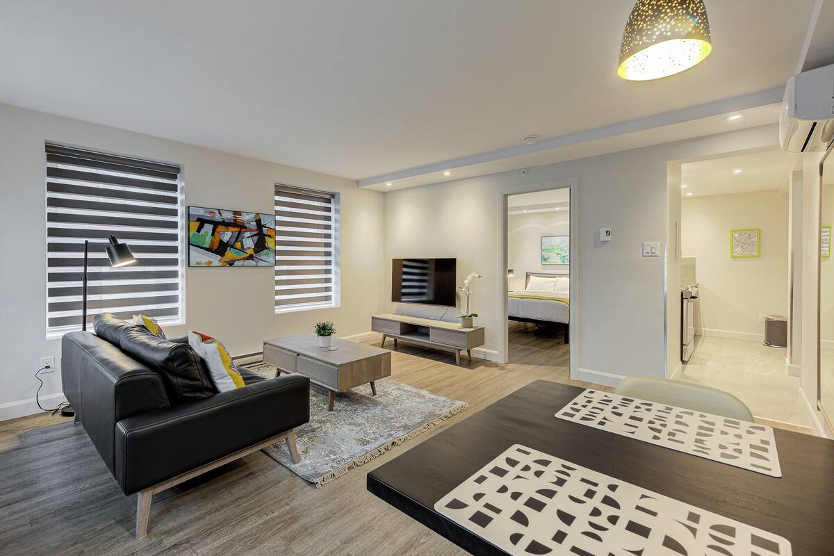 A modern living room with a sofa, coffee table, TV, and artwork.