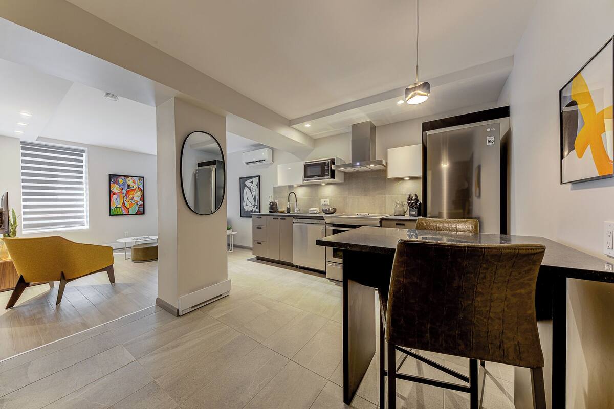 A modern kitchen with a central island, stainless steel appliances, and a dining area with a table and chairs.