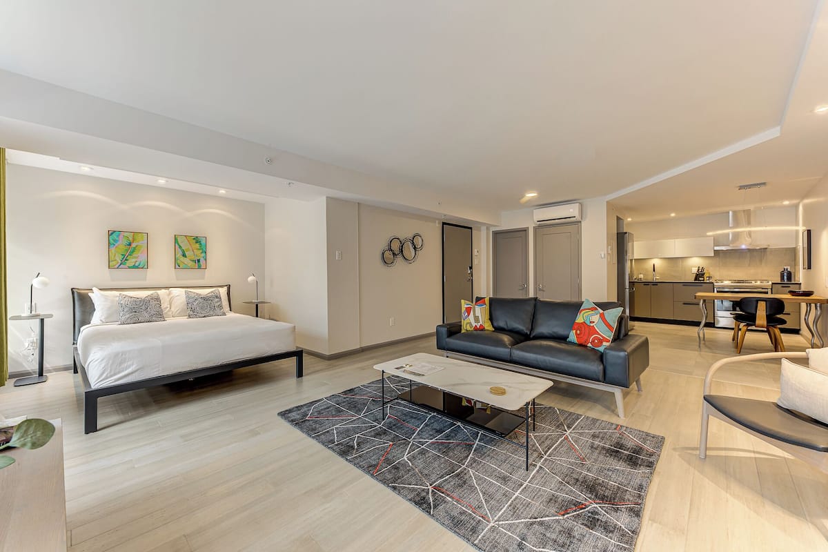 A modern living room with a bed, sofa, and dining area.