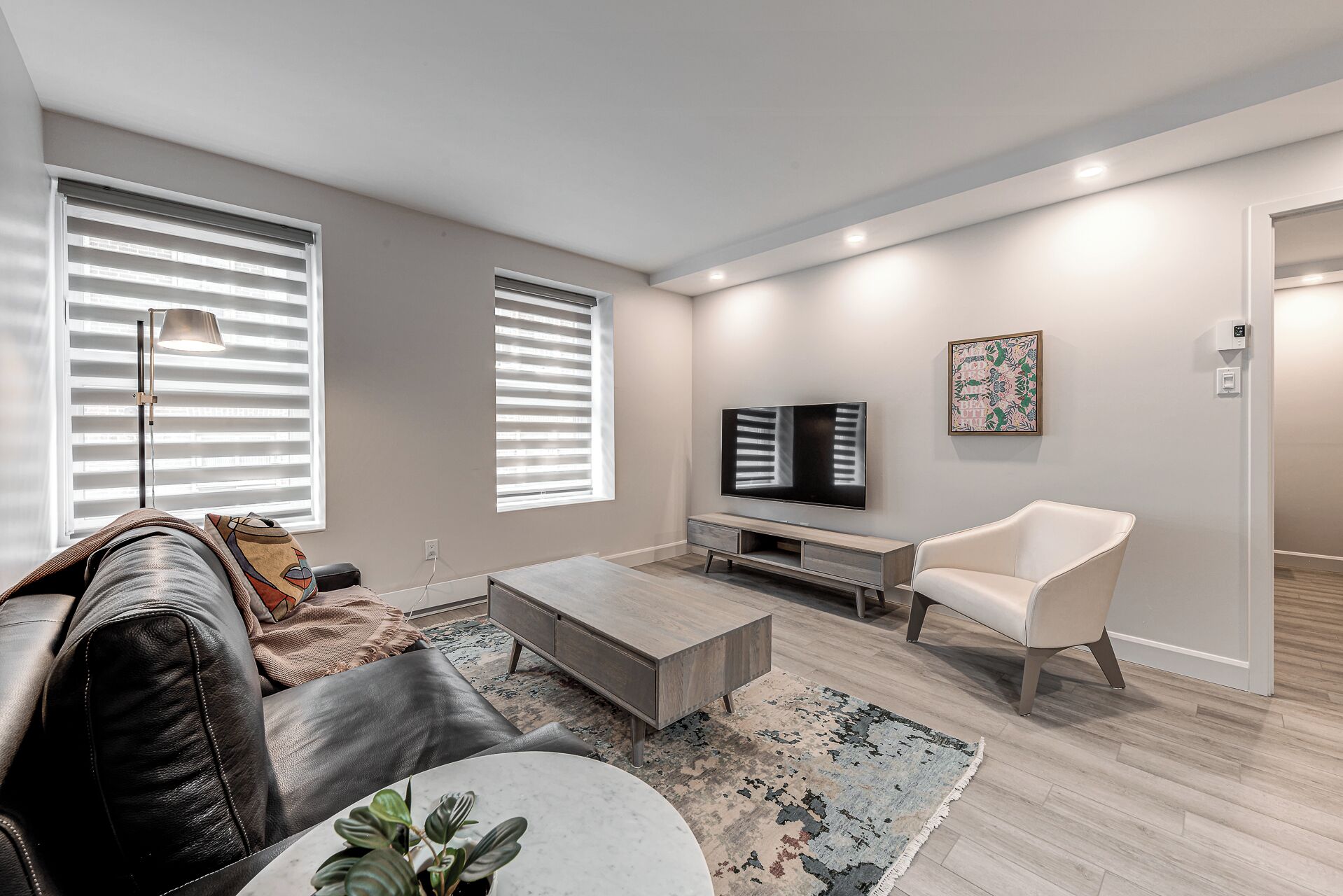 A modern living room with a sofa, coffee table, TV, and a chair.