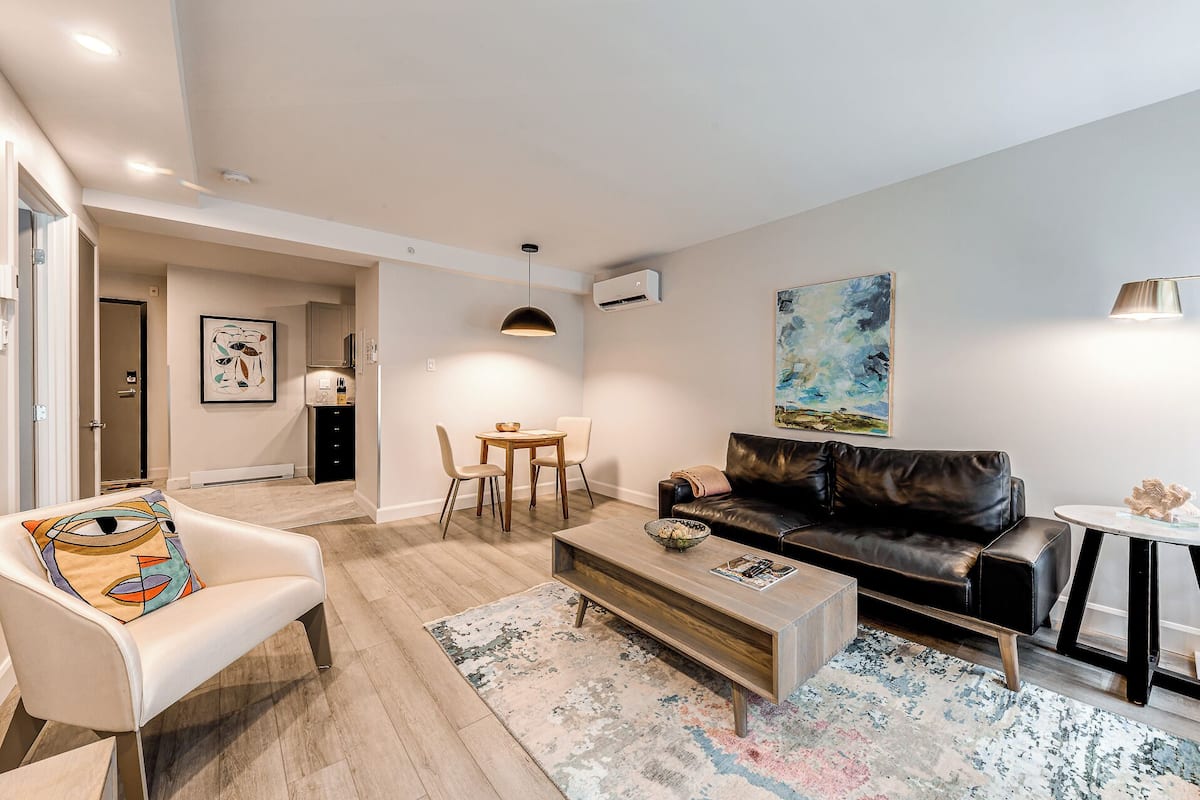 A modern living room with a leather sofa, a coffee table, and a dining area with a table and chairs.