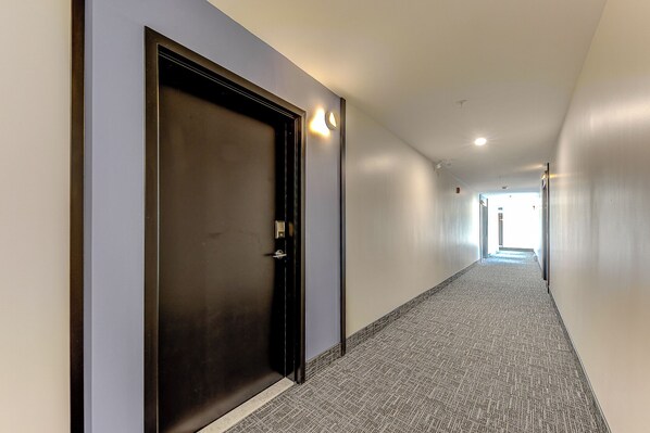 A long, narrow hallway with a carpeted floor and a closed door on the left. - 77 St-Vallier Appart Hôtel (Québec)