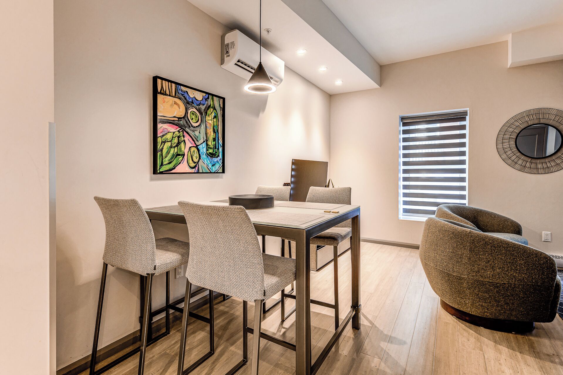 Un comedor moderno con una mesa, sillas y un cuadro en la pared.