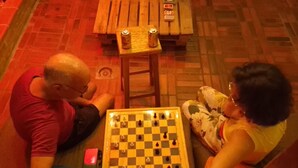 Two people playing chess on a wooden table with a checkered board. - Adventure hostel (San Gil)