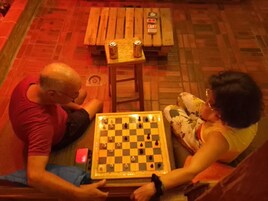 Dos personas jugando ajedrez sobre una mesa de madera con tablero de cuadros.