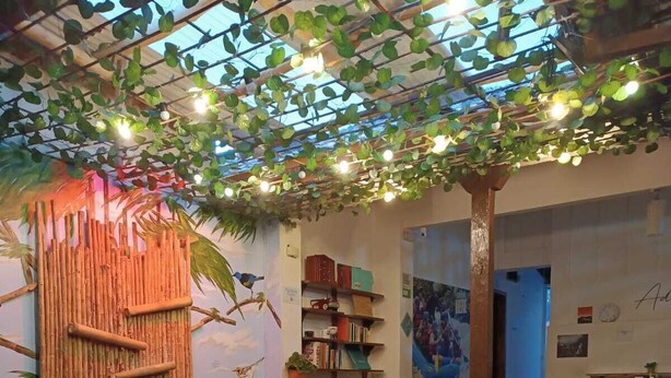 A cozy indoor space with a bamboo wall, a sofa, a coffee table with a chess set, and a bookshelf. - Adventure hostel (San Gil)
