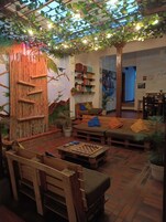Un espacio interior acogedor con una pared de bambú, un sofá, una mesa de centro con un juego de ajedrez y una estantería.