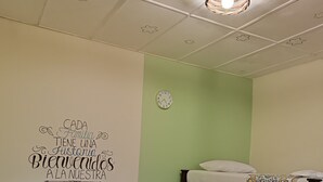A room with a bunk bed, a single bed with patterned bedding, a wall clock, and a ceiling with star-shaped cutouts. - Adventure hostel (San Gil)