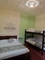 Una habitación con una litera, una cama individual con ropa de cama estampada, un reloj de pared y un techo con formas de estrella.