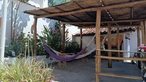 A wooden pergola with a hammock, a small wooden stool, and a red toy car. - Adventure hostel (San Gil)