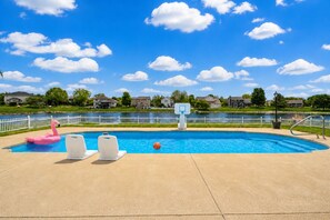 A swimming pool with a basketball hoop, lounge chairs, and a pink flamingo float.