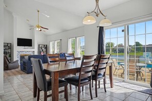 A spacious living area with a dining table, chairs, a sofa, and a TV.