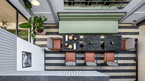 Un intérieur moderne comprenant un coin salon, un banc rembourré de couleur verte et une table à manger avec des chaises.
