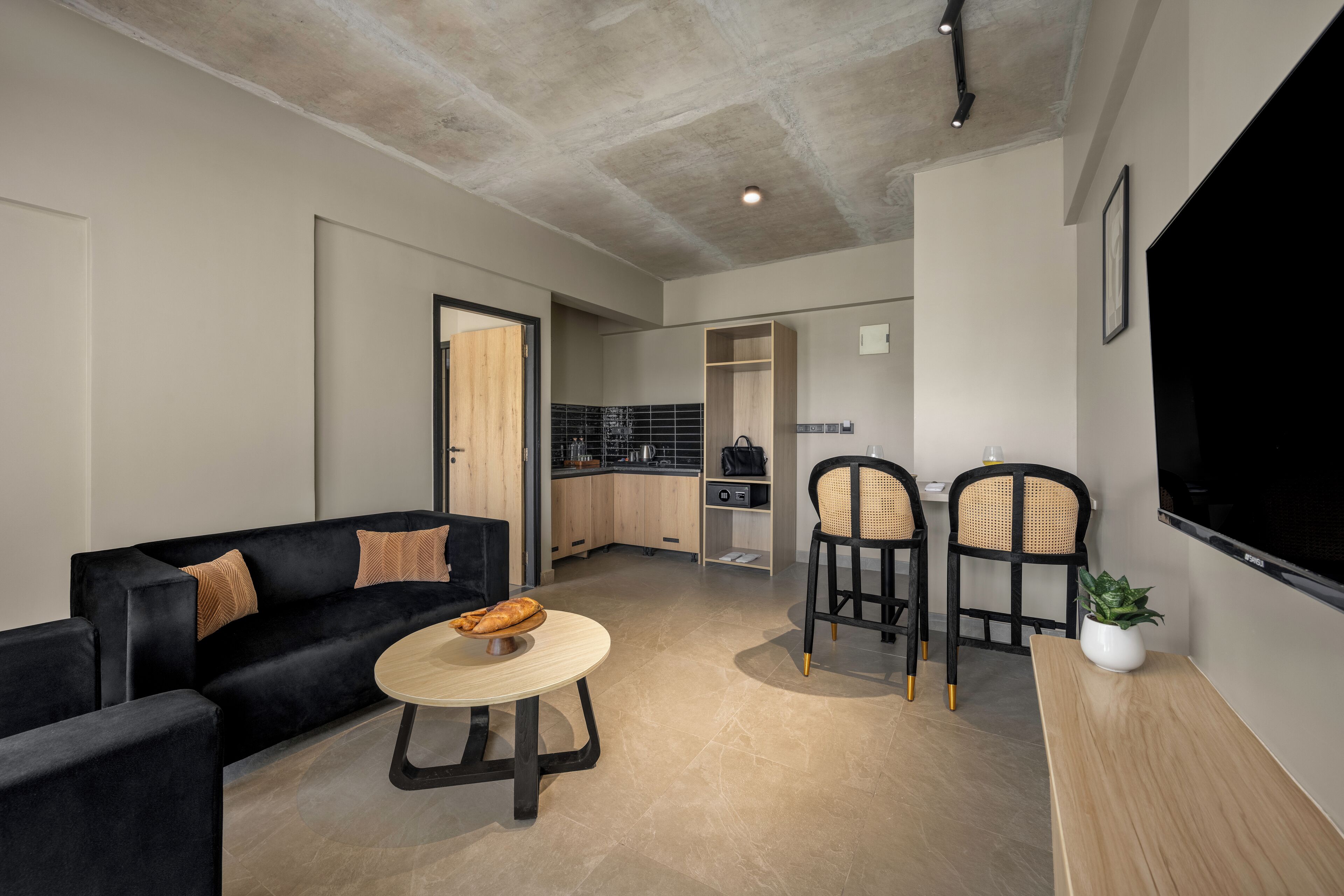A modern living room with a black sofa, a round coffee table, and two wicker chairs.