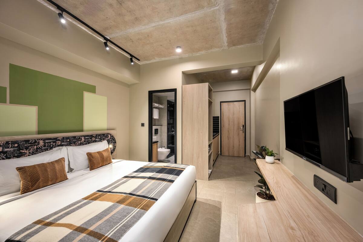 Une chambre d’hôtel moderne dotée d’un grand lit, d’une télévision et d’un dressing.