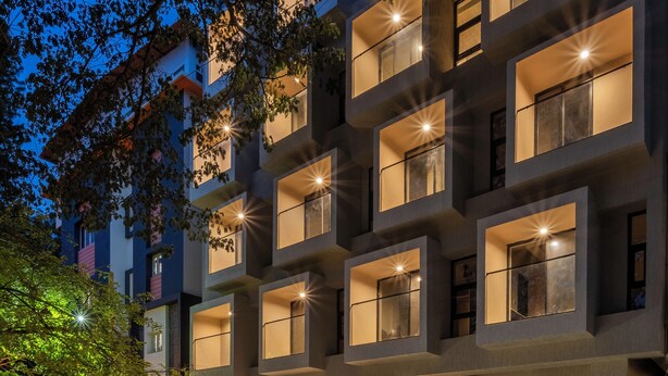 Un immeuble à plusieurs étages, doté de fenêtres illuminées et d’une entrée bien visible.