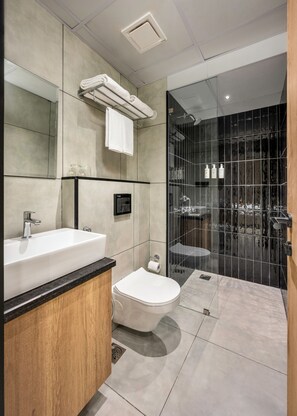 Een moderne badkamer met een groot wastafel, toilet en een douchecabine met glazen wanden.