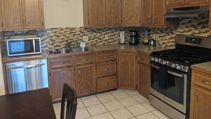 Una cocina con armarios de madera, microondas, cafetera y estufa.