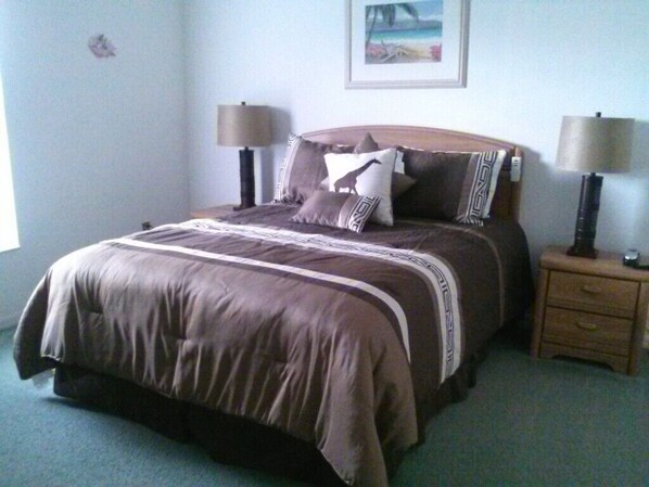A neatly made bed with a brown and white bedspread, two bedside lamps, and a small wooden nightstand with a lamp.