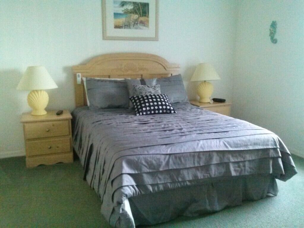 Une chambre à coucher avec un lit, deux tables de chevet et une commode.