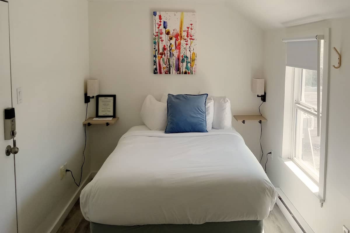 Una camera da letto con un letto, un quadro, comodini e una finestra.