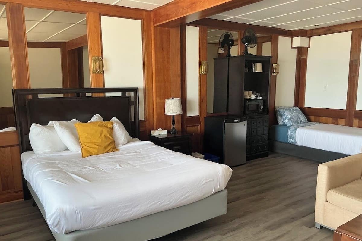 Una camera d'albergo con un letto grande, una scrivania con una lampada, una cassettiera e un divano.